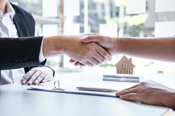 Finishing to successful deal of real estate, Broker and client shaking hands after signing contract approved application form, concerning mortgage loan offer for and house insurance