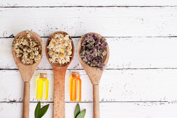 Wooden spoons with dried medicinal herbs and bottles with essence. Medicinal teas and tinctures as...
