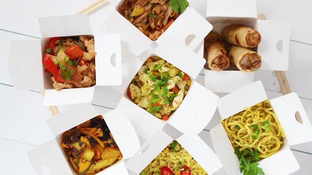 Various oriental dishes packed in paper box. Food is delivered on the table. Asian take away concept
