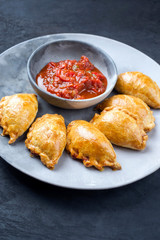 Traditional South American empanada de carne offered with a chili dip as closeup on a modern design plate