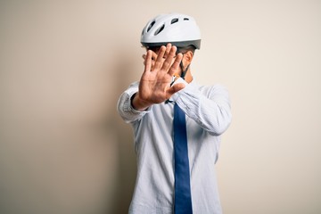 Young businessman wearing glasses and bike helmet standing over isolated white bakground covering eyes with hands and doing stop gesture with sad and fear expression. Embarrassed and negative concept.