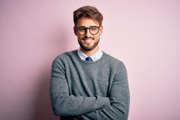 Young handsome man with beard wearing glasses and sweater standing over pink background happy face...