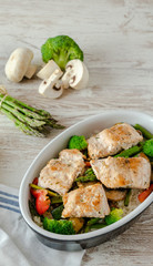 Fuente con salmón salvaje, arroz, esparragos trigueros, brócoli, pimiento rojo y champiñones sobre mesa blanca. 