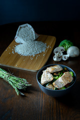 bol de salmón salvaje, arroz, esparragos trigueros, brócoli, pimiento rojo y champiñones sobre mesa marrón. Dark photography. 