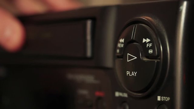 Male Hand Inserting VHS Cassette Tape In A VHS Player. Close-Up.  