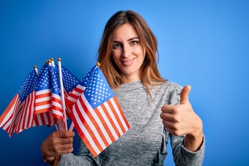 Young beautiful patriotic woman holding united states flags celebrating inependence day happy with...