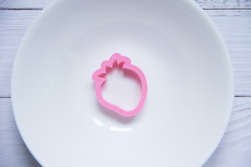 The pink strawberry shape made of plastic on a white background. The children's form for plasticine
