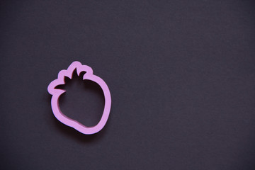 the strawberry in pink plastic on a black background. children's form for plasticine.