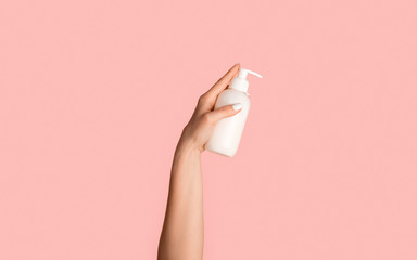 Close up of girl holding bottle with dispenser on pink background