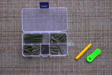 A box with elements of carp accessories lies near needle and a drill for boilies