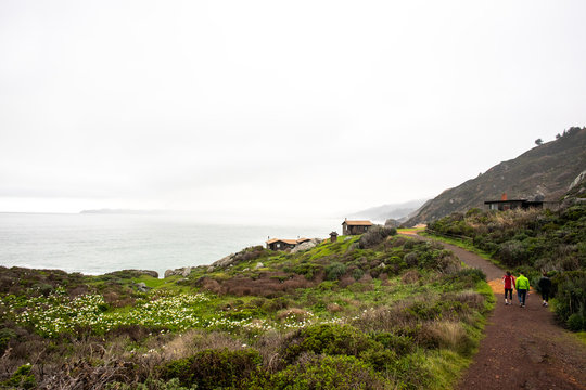 A group of people hiking together in a rural area near cabins on the Pacific coast.