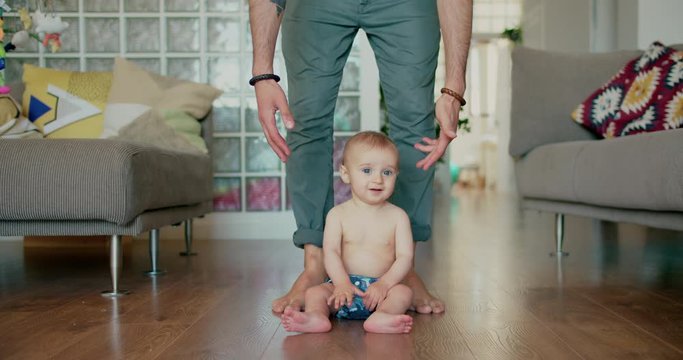 Smiling Newborn baby boy doing his first steps with daddy help at home. Lovely family and gentle paranting.