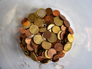 A jar glas full of old coins pictured from above