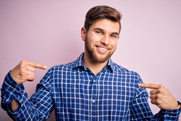 Young handsome blond man with beard and blue eyes wearing casual shirt standing looking confident with smile on face, pointing oneself with fingers proud and happy.