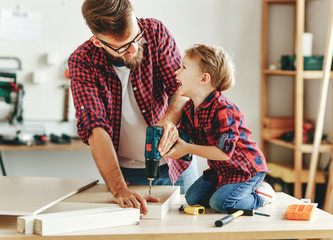 Happy father and son assembling furniture on table.