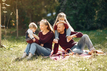 Fototapeta premium Family in a autumn park. Woman in a red sweater. Cute childrens with parents