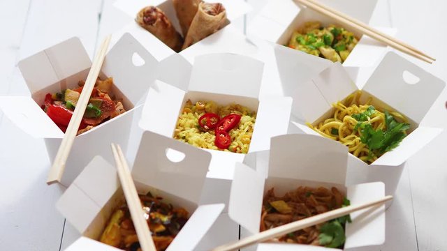 Various oriental dishes packed in paper box. Food is delivered on the table. Asian take away concept