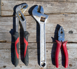 work tools on a old wooden background. adjustable wrenches and pliers.