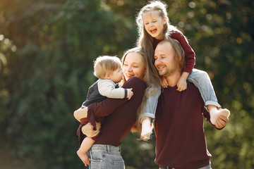 Fototapeta premium Family in a autumn park. Woman in a red sweater. Cute childrens with parents