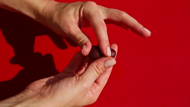 top view on woman hands form eggplant shape candy from marzipan mass