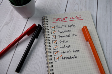 Student Loans write on a book. Supported by an additional services isolated on wooden background.