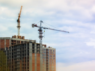 Construction of an apartment building in the city: construction crane against the sky, titl-shift