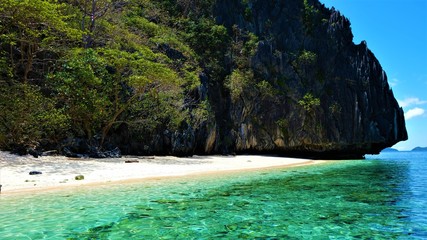 Colorful beach without human. Beautiful white sand, blue sky, green sea and rocks.