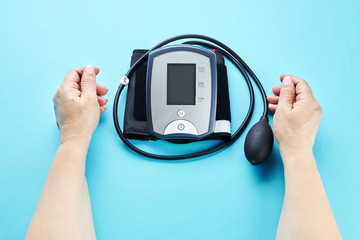 measuring blood pressure with electronic medical device over blue background.