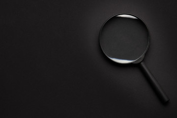search concept. black on black. magnifier on dark background. view from above. copy space for...