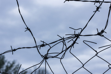 Metal barbed wire against a blue sky background: imprisonment and slavery