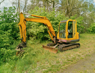 shovel excavator in the forest with soft light framed by green bushes
