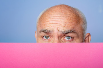 Funny senior man holding empty paper. Close up face. Presentation. Copyspace. Booklet design sheet display read first person. Season sales. Surprised man holding empty paper.