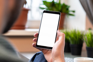 Man Holding Phone With Blank Screen and Calling By Video Chat From Cozy Home. Online Communication With Friends And Family. Copy Space. Empty Space