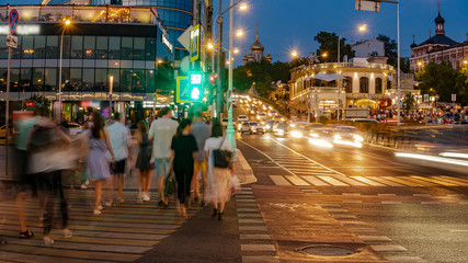 Traffic flows of people and cars at the busy city crossroad