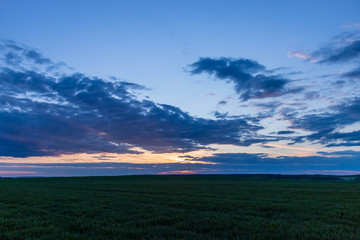 coloured sky with amazing clouds and  green fields below 