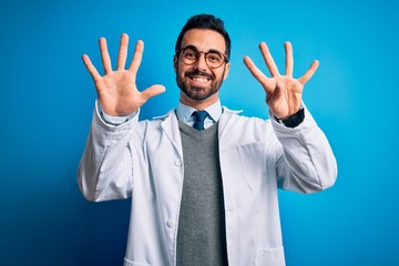 Young handsome doctor man with beard wearing coat and glasses over blue background showing and pointing up with fingers number nine while smiling confident and happy.