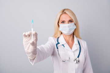 New antidote corona virus vaccine concept. Experienced pensioner retired woman doc wear respiratory mask stethoscope rubber latex gloves hold syringe needle isolated gray color background