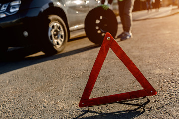 Worker changes a broken wheel of a car. The driver should replace the old wheel with a spare