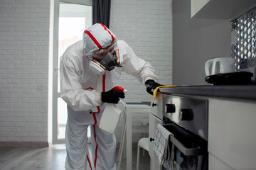 disinfection of coronavirus in the apartment. People in protective suits make professional cleaning of the room from viruses and diseases