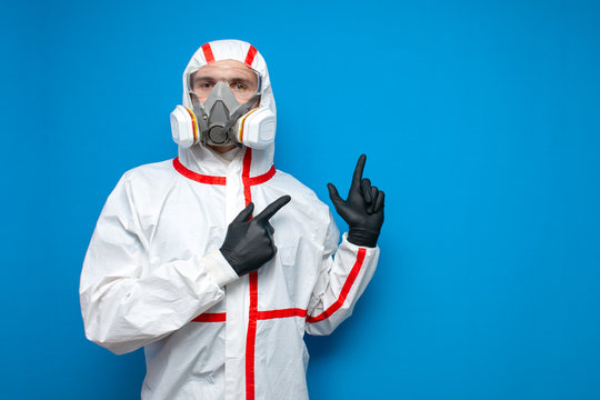 disinfector man in a protective suit shows a place for text on a blue isolated background, disinfection service worker, coronavirus concept