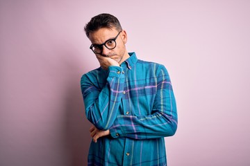 Young handsome man wearing casual shirt and glasses standing over isolated pink background thinking looking tired and bored with depression problems with crossed arms.
