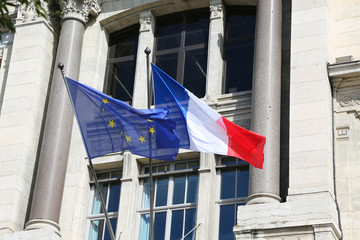 Flag of France and the flag of the European Union are next to the window of a house in the city of Lyon in France.