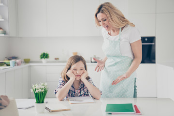 Two people angry furious mother scream her daughter kid sit table cant write homework lesson courses feel bored annoyed in kitchen house indoors