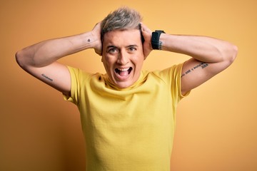 Fototapeta na wymiar Young handsome modern man wearing yellow shirt over yellow isolated background Crazy and scared with hands on head, afraid and surprised of shock with open mouth