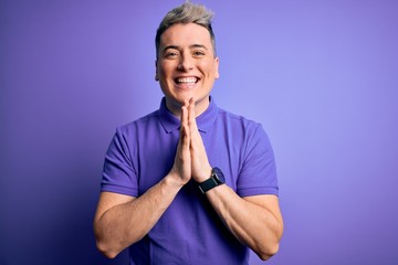 Young handsome modern man wearing casual purple t-shirt over isolated background praying with hands together asking for forgiveness smiling confident.