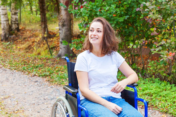 Young happy handicap woman in wheelchair on road in hospital park waiting for patient services....