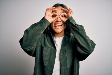 Young beautiful asian woman wearing casual shirt standing over isolated white background doing ok gesture like binoculars sticking tongue out, eyes looking through fingers. Crazy expression.