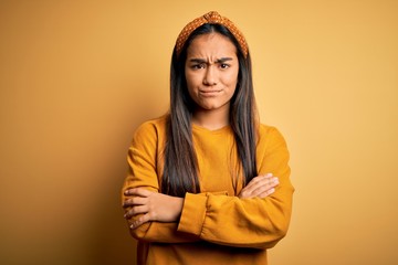 Young beautiful asian woman wearing casual sweater and diadem over yellow background skeptic and...