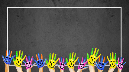 School background background - Many brightly painted children's hands in front of a old aged empty blackboard with white frame and space for text
