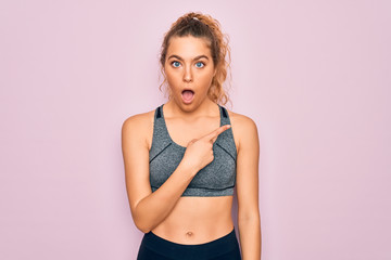 Young beautiful blonde sportswoman with blue eyes doing exercise wearing sportswear Surprised pointing with finger to the side, open mouth amazed expression.